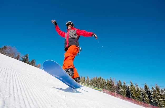 Snowboarder no ar enquanto andava na encosta nas montanhas em um lindo dia ensolarado de inverno