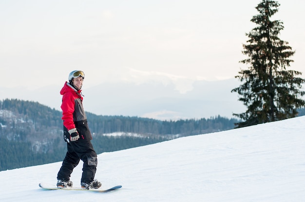 Snowboarder de pie en la cima de una montaña