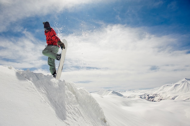 Snowboarder de salto manteniendo la mano en el snowboard