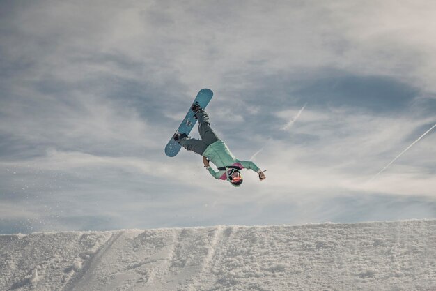 Snowboarder springt gegen den Himmel auf dem Berg