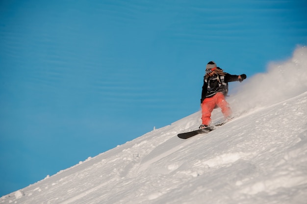 Snowboarder-Typ mit Dreadlocks, die den Hügel im beliebten Touristenort Gudauri in Georgia reiten