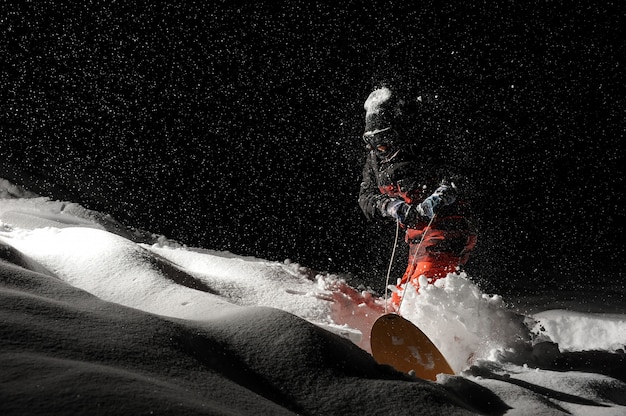 Snowboarder vestido com o sportswear laranja andando com o snowboard