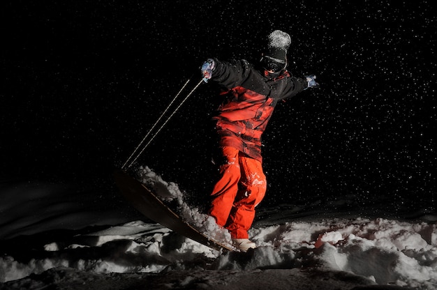 Snowboarder vestido con la ropa deportiva naranja balanceándose en el tablero