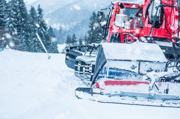 Snowcat ratrac rojo trabajando en la pista de esquí.