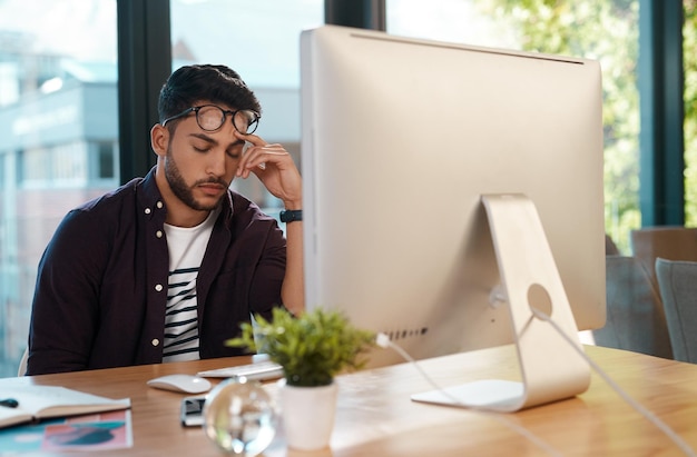 So schläfrig Schnappschuss eines hübschen jungen Geschäftsmanns, der sich überfordert fühlt und einschläft, während er in seinem Büro an seinem Computer sitzt