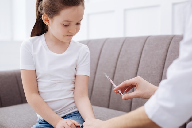 Só uma pequena injeção. adorável doce jovem recebendo injeção anual de antigripal enquanto toma tudo com coragem e fica sentada quieta