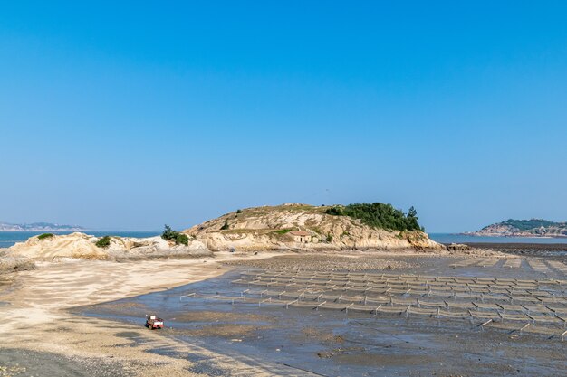 Sob o céu azul, as linhas e texturas das jangadas e cordas de bambu na fazenda de algas na praia são muito bonitas