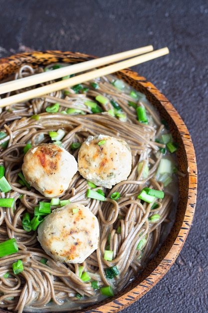 Soba-Nudeln, serviert mit Hühnerfleischbällchen und Frühlingszwiebeln.