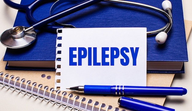 Sobre a mesa estão blocos de notas, um estetoscópio, uma caneta e uma folha de papel com os textos epilepsia. conceito médico