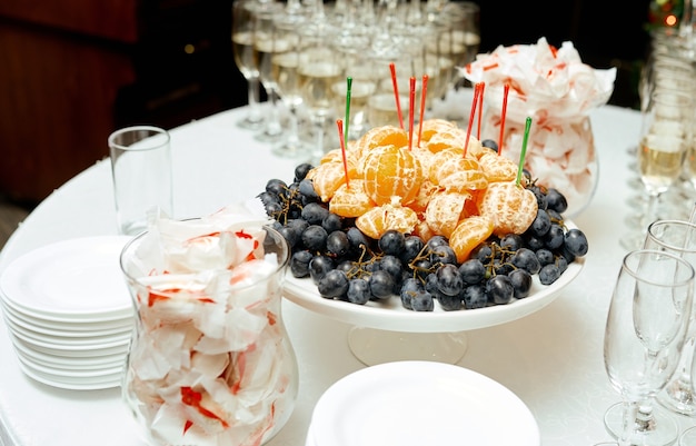 Sobre a mesa, um prato de frutas doces e potes de bombons. Foto de alta qualidade