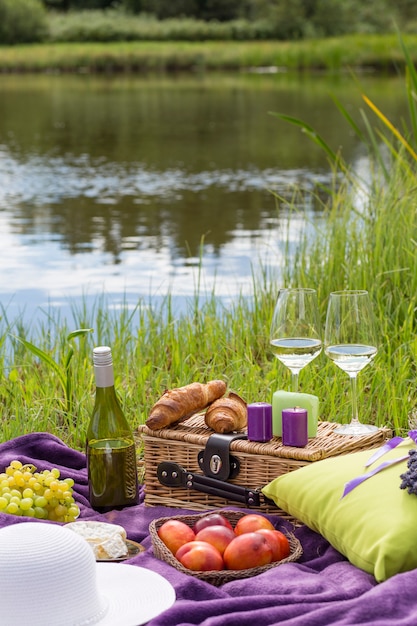 Sobre la alfombra morada hay una almohada, un ramo de lavanda, una botella de vino, croissants.