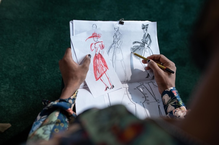 Foto sobre el ángulo de las manos del diseñador de moda masculino no binario creando bocetos