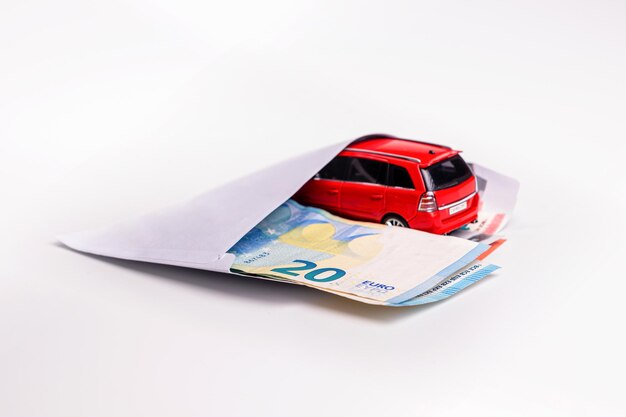 Sobre con billetes en euros y coche aislado en concepto de planificación de costes de transporte blanco