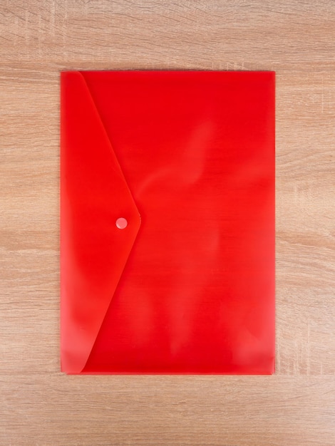 Sobre de carpeta de plástico rojo para documentos aislado sobre fondo azul.