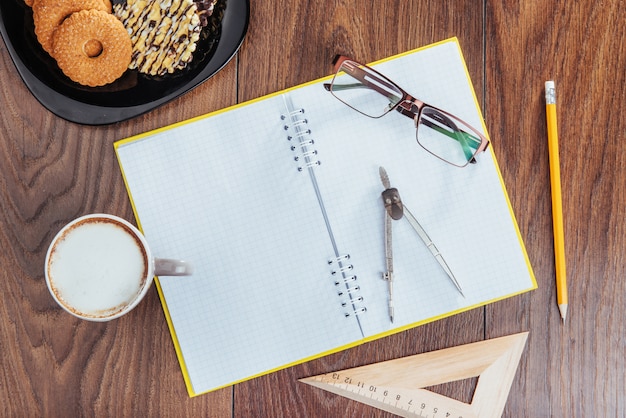 Sobre cuaderno de madera lápiz, café y flores.