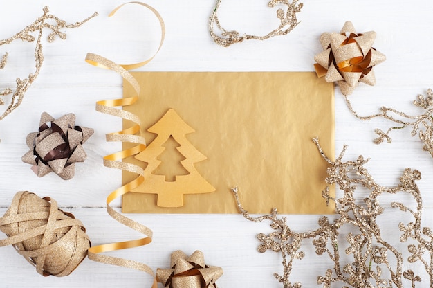 Sobre dorado en blanco, nota vacía y juguetes de Navidad dorados sobre fondo rústico de madera