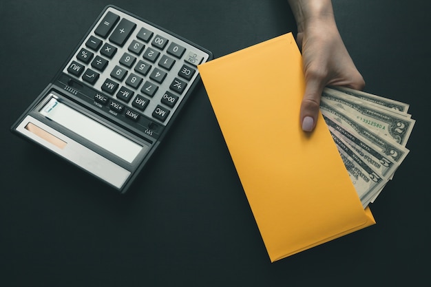 Sobre el escritorio de cuero negro una calculadora, la niña sostiene en su mano un sobre amarillo con dinero.