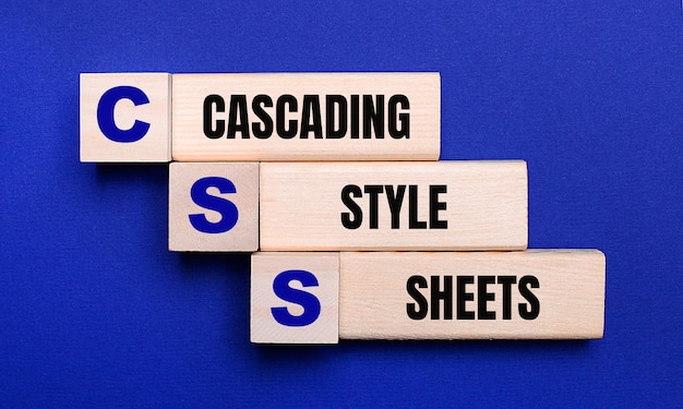 Sobre un fondo azul brillante, bloques y cubos de madera claros con el texto Hojas de estilo en cascada CSS