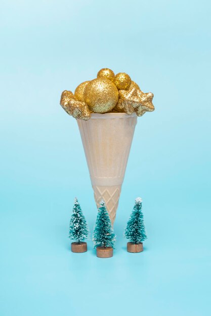 Sobre un fondo azul, un cono de helado de navidad con bolas de oro estrellas concepto de vacaciones mínimo vertical