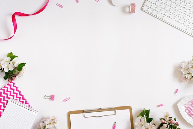 Sobre un fondo blanco plano con teclado de flores de manzana y clips de papelería, un escritorio floral femenino El concepto de una elegante vista superior de la mañana de primavera y espacio de copia