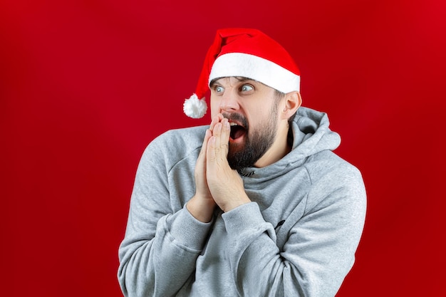 Sobre un fondo navideño amarillo un hombre que sostiene juguetes navideños, bolas de color dorado en sus manos, sonríe a la cámara, las levanta frente a él.