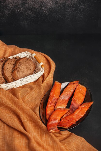 sobre un fondo oscuro en un plato se colocan rebanadas de pescado rojo ahumado con pan rebanado