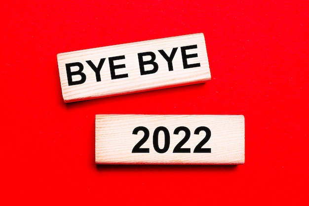 Sobre un fondo rojo brillante hay dos bloques de madera clara con el texto BYE BYE 2022