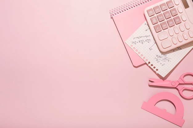 Sobre un fondo rosa, la escuela rosa suministra una calculadora con hojas de trucos.