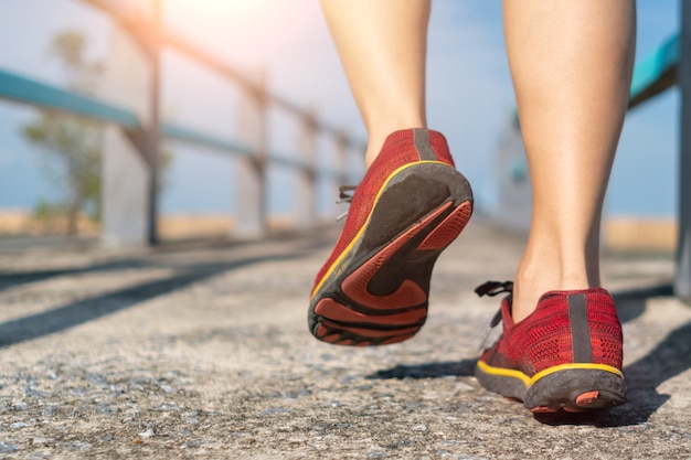 Sobre un fondo verde, una mujer camina y corre con zapatos para correr. El ejercicio para la salud es una noción.