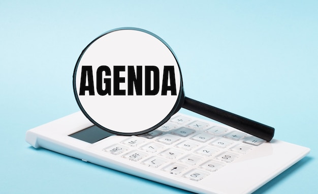 Sobre fundo azul, calculadora branca e lupa com o texto AGENDA. Conceito de negócios