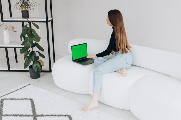 Sobre el hombro de una mujer escribiendo en una computadora portátil con una pantalla keygreen