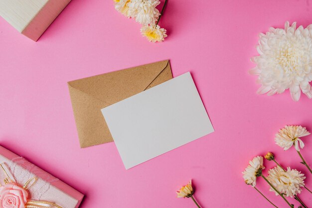 sobre marrón caja de regalo rosa con tarjeta en blanco y flor sobre fondo rosa