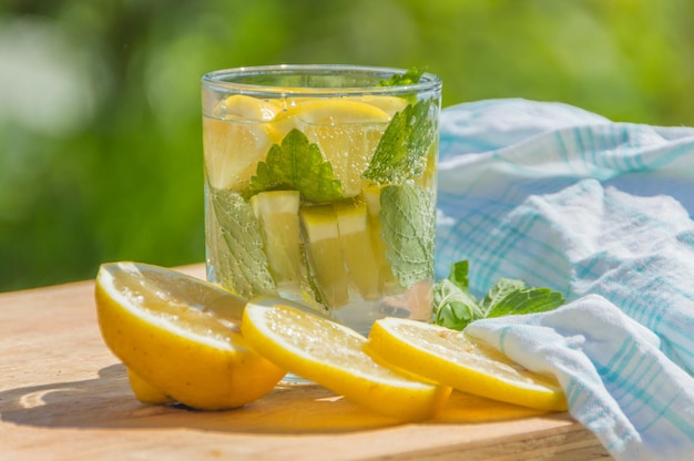 Sobre una mesa agua con gas con limón y menta.