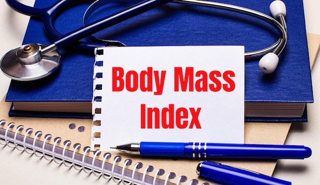 Sobre la mesa hay blocs de notas, un estetoscopio, un bolígrafo y una hoja de papel con el texto Índice de masa corporal IMC Concepto médico