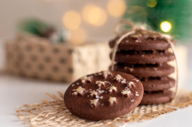 Sobre la mesa hay una pila de galletas navideñas de chocolate redondas y un vaso de leche.