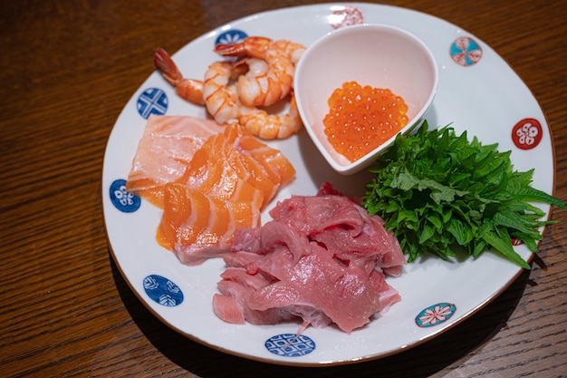 Sobre una mesa hay un plato de salmón, salmón y caviar.