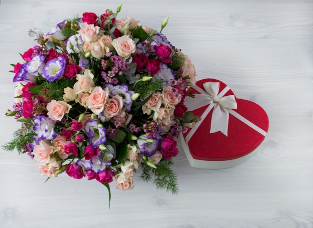 Foto sobre la mesa un hermoso ramo de flores y un regalo.