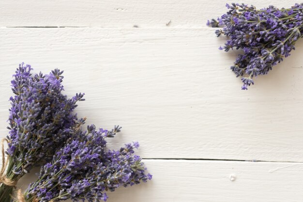 Sobre la mesa de madera hay ramos violetas de flores de lavanda para herbario. Endecha plana