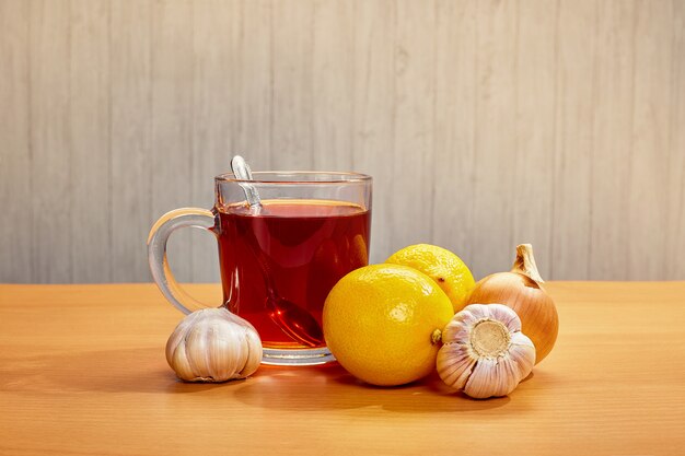 Sobre la mesa taza con té limones ajo cebollas