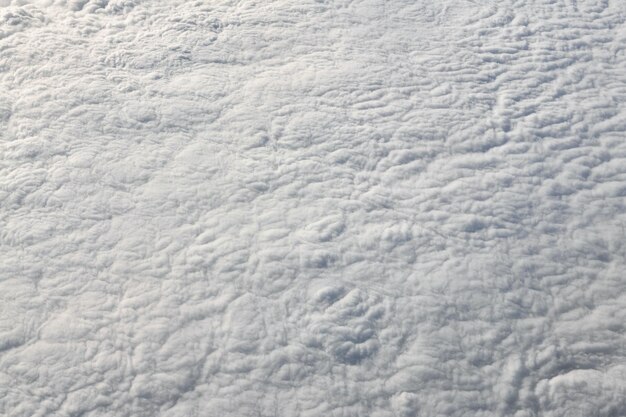 Sobre las nubes vista superior desde la ventana del avión gruesas nubes blancas azules parecen espuma blanda