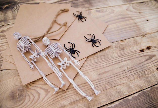 Un sobre de papel kraft y esqueletos de fieltro, arañas, alrededor sobre un fondo de madera. Decoración de Halloween. Decoraciones navideñas hechas a mano.