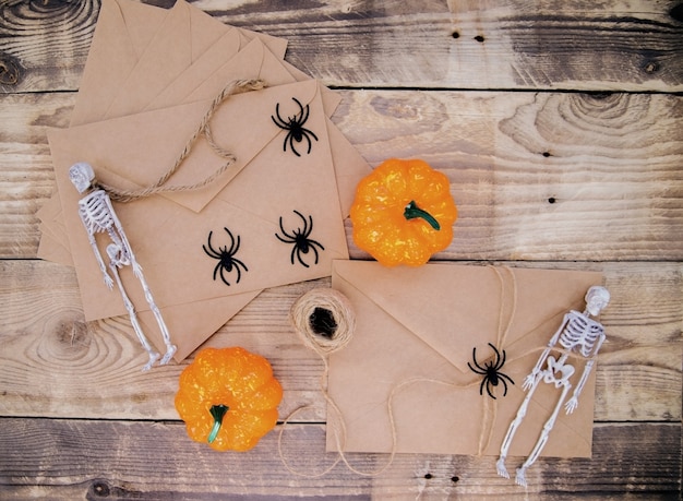 Un sobre de papel kraft y murciélagos de fieltro, esqueletos, arañas, calabazas alrededor sobre un fondo de madera. Decoración de Halloween. Decoraciones navideñas hechas a mano.