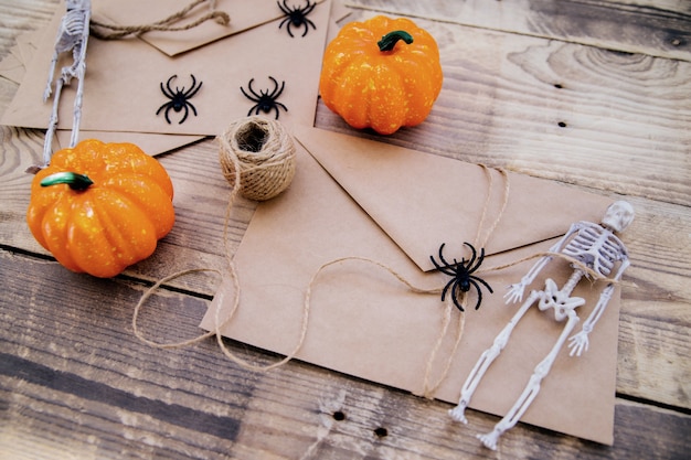 Un sobre de papel kraft y murciélagos de fieltro, esqueletos, arañas, calabazas alrededor sobre un fondo de madera. Decoración de Halloween. Decoraciones navideñas hechas a mano.