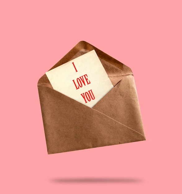 Un sobre de papel kraft vintage con una hoja de papel con la inscripción "Te quiero" en fondo rosa concepto de carta de amor