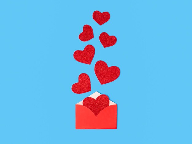 Sobre rojo con corazones para el día de San Valentín sobre fondo azul concepto para el día de San Valentín