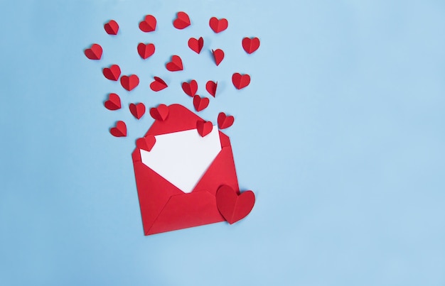 Sobre rojo con corazones rojos sobre fondo azul, tarjeta para texto y espacio de copia