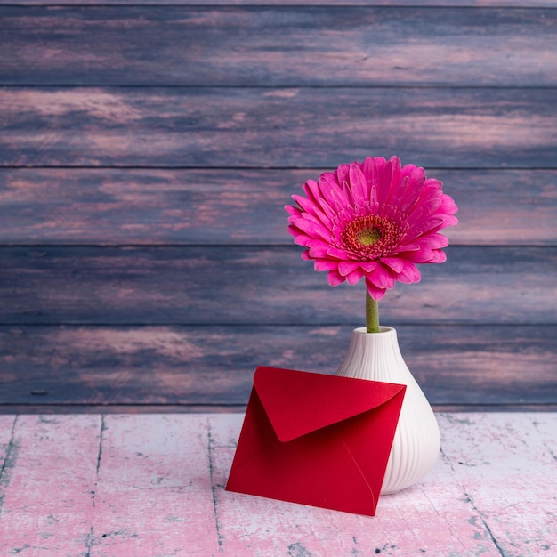 Un sobre rojo con una flor y un sobre rojo en el jarrón.