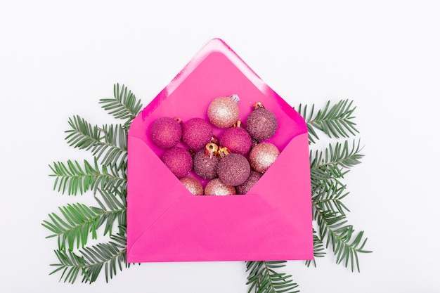 Sobre rosa con bolas brillantes y ramas de un árbol de Navidad sobre un fondo gris El concepto de celebrar la Navidad y cartas a Santa Claus