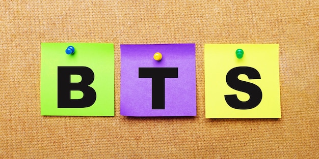 Sobre una superficie beige, pegatinas multicolores para notas con la palabra BTS