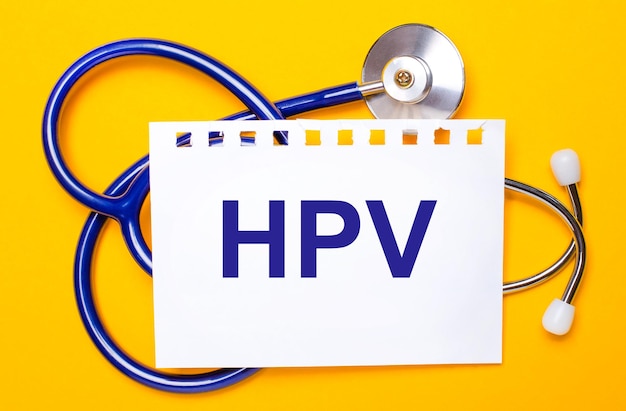 Sobre um fundo amarelo brilhante, um estetoscópio azul e uma folha de papel com o texto HPV Medical concept